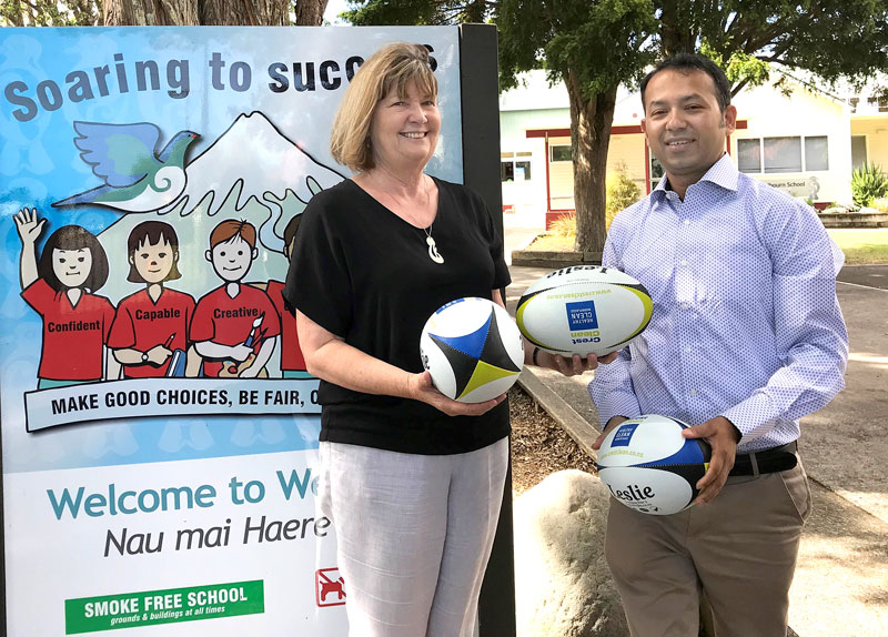 Kay Crofskey, Principal of Welbourn School, receives rugby balls from Prasun Acharya, CrestClean’s Taranaki Regional Manager.