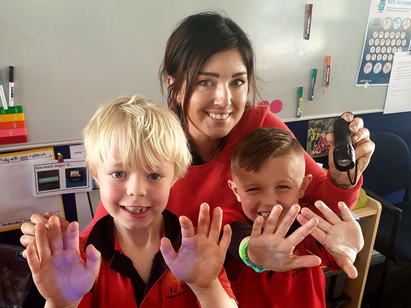 Two youngsters check for “invisible germs” on their hands during a session on hand-hygiene presented by Gina Holland.