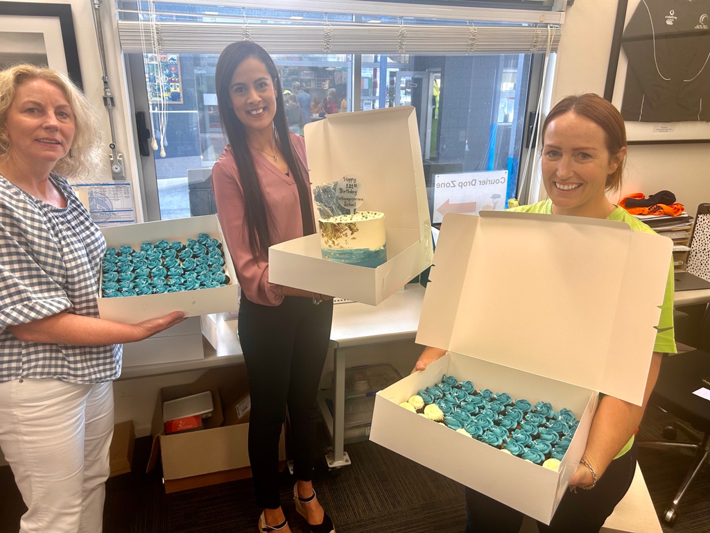 North Harbour Business Development Manager, Rachel Kumar, gifts cake and cupcakes to Whangaparāoa Primary School staff.